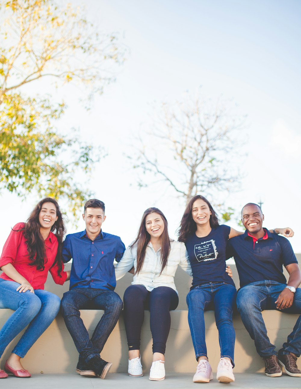 A diverse group of young people standing arm in arm, smiling.