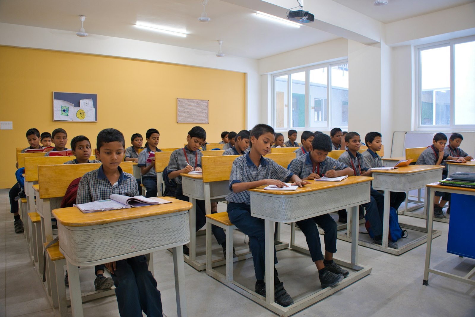 Rows of uniformed students writing at their desks during class.